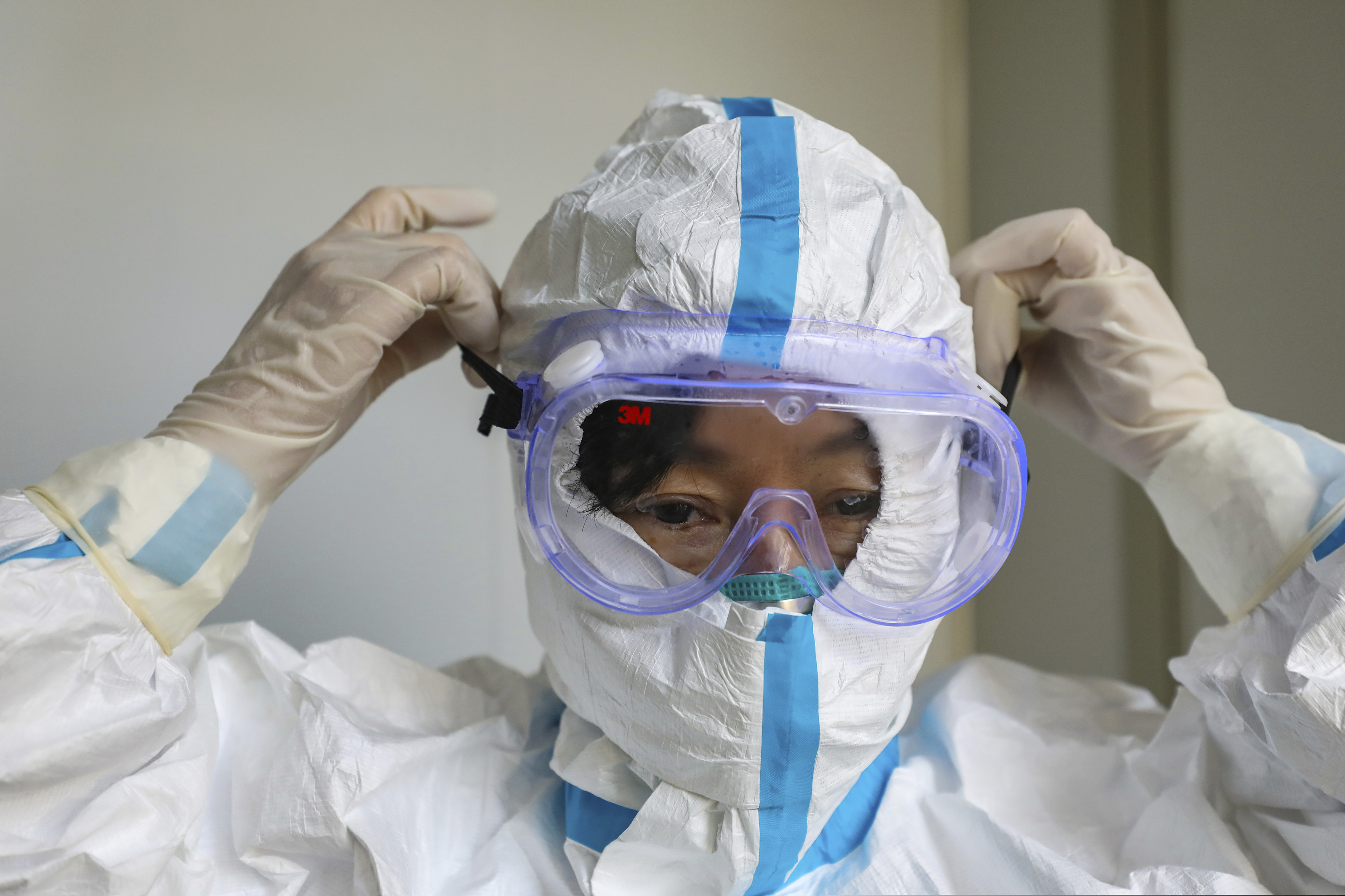 (Chinatopix via AP) A doctor puts on a protective suit and goggles at a hospital in Wuhan in central China's Hubei Province, Thursday, Jan. 30, 2020. China counted 170 deaths from a new virus Thursday and more countries reported infections, including some spread locally, as foreign evacuees from China's worst-hit region returned home to medical observation and even isolation.