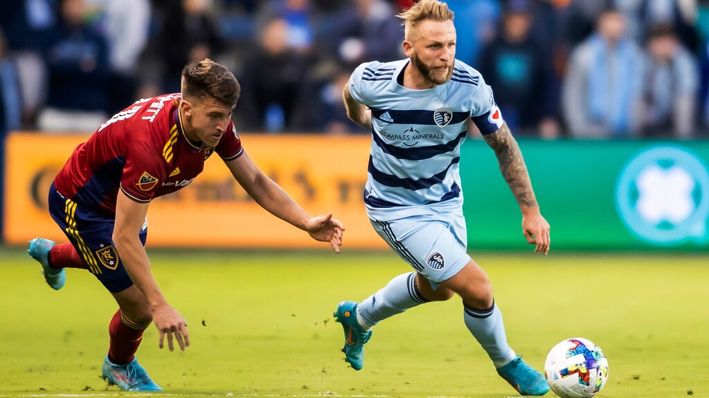 Sporting Kansas City forward Johnny Russell (7) powers past Real Salt Lake forward Tate Schmitt (21) during an MLS soccer match Saturday, March 26, 2022, in Kansas City, Kan. (AP Photo/Nick Tre. Smith)