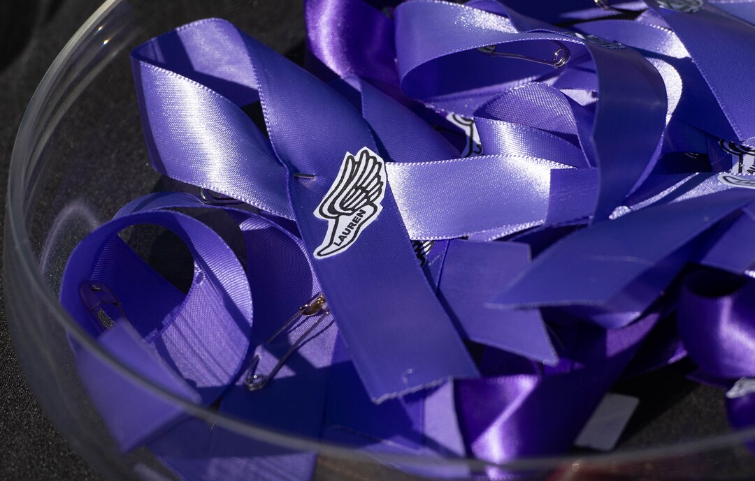 (Francisco Kjolseth  |  The Salt Lake Tribune) Purple ribbons are handed out to people gathered for a memorial walk on the track where University of Utah student and track athlete Lauren McCluskey used to compete on the two-year anniversary of her murder on Thursday, Oct. 22, 2020.