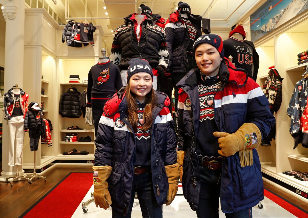 Ice dancing pair Maia Shibutani, left, and Alex Shibutani, a brother and sister team, pose for photographs wearing Team USA Opening Ceremony uniforms designed by David Lauren for Polo Ralph Lauren, Monday, Jan. 22, 2018, outside the brand's Prince Street store in New York. The parkas have a battery-operated, built-in heating element that can be adjusted using a cell phone. The clothing will be worn at the upcoming Winter Olympics in South Korea. (AP Photo/Kathy Willens)