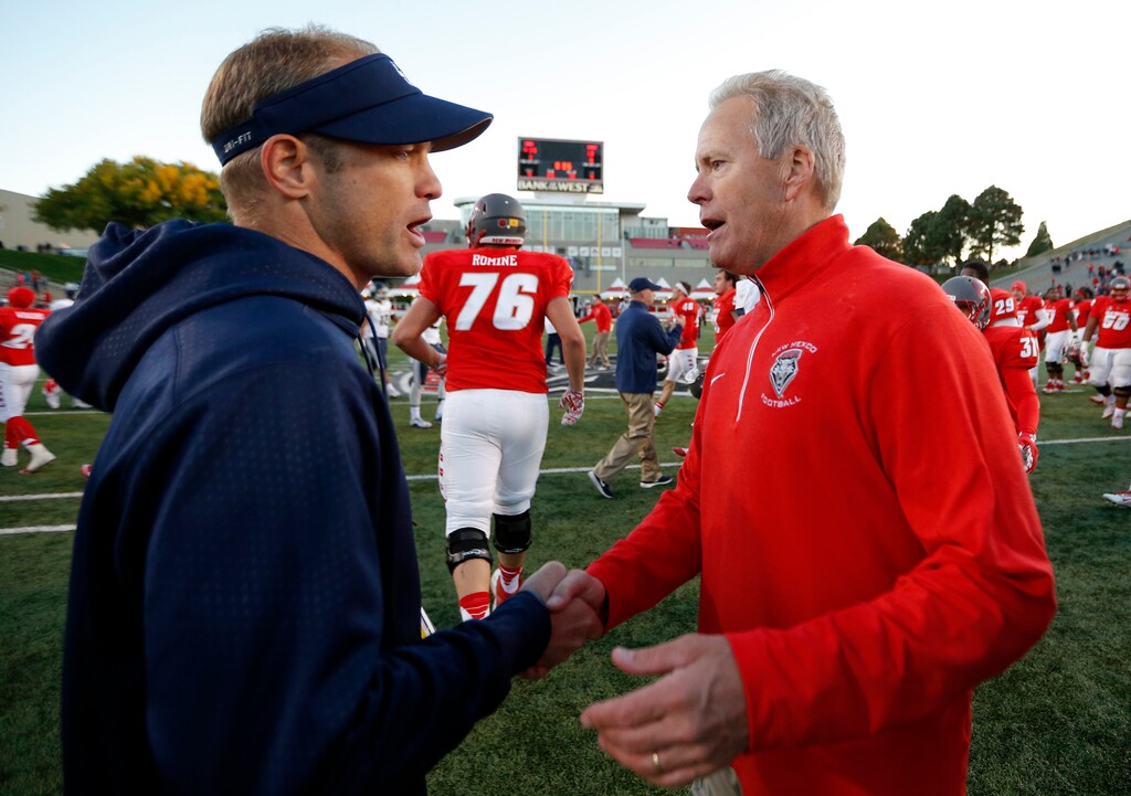 New Mexico head coach Bob Davie, right, is congratulated by Utah State head coach Matt Wells at the end of an NCAA college football game in Albuquerque, N.M., Saturday, Nov. 7, 2015. New Mexico won 14-13. (AP Photo/Andres Leighton)