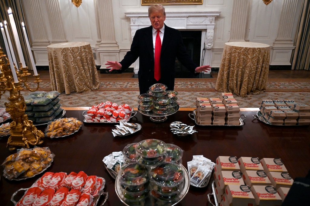 In this Jan. 14, 2019 photo, President Donald Trump talks to the media about the table full of fast food in the State Dining Room of the White House in Washington, for the reception for the Clemson Tigers. The partial government shutdown is hitting home for President Trump in a very personal way. He lives in government-run housing, after all. Just 21 of the roughly 80 people who help care for the White House _ from butlers to electricians to chefs _ are reporting to work. The rest have been furloughed. (AP Photo/Susan Walsh)