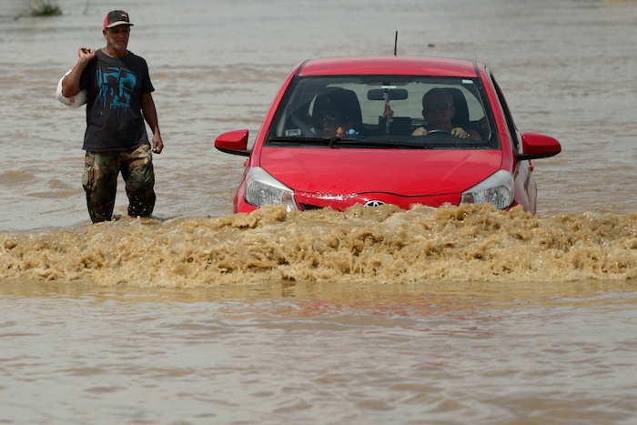 A resident walks on a flooded road after the passing of Hurricane Maria, in Toa Baja, Puerto Rico, Friday, September 22, 2017. Because of the heavy rains brought by Maria, thousands of people were evacuated from Toa Baja after the municipal government opened the gates of the Rio La Plata Dam. (AP Photo/Carlos Giusti)