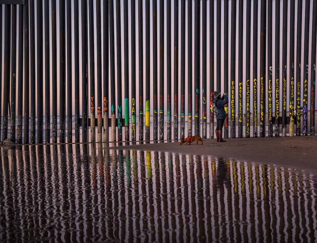 A woman takes a snapshot by the border fence between San Diego, Calif., and Tijuana, as seen from Mexico, Thursday, Jan. 3, 2019. Discouraged by the long wait to apply for asylum through official ports of entry, many migrants from recent caravans are choosing to cross the U.S. border wall and hand themselves in to border patrol agents. (AP Photo/Daniel Ochoa de Olza)