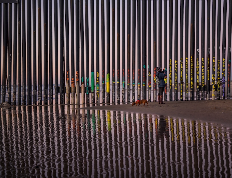 A woman takes a snapshot by the border fence between San Diego, Calif., and Tijuana, as seen from Mexico, Thursday, Jan. 3, 2019. Discouraged by the long wait to apply for asylum through official ports of entry, many migrants from recent caravans are choosing to cross the U.S. border wall and hand themselves in to border patrol agents. (AP Photo/Daniel Ochoa de Olza)