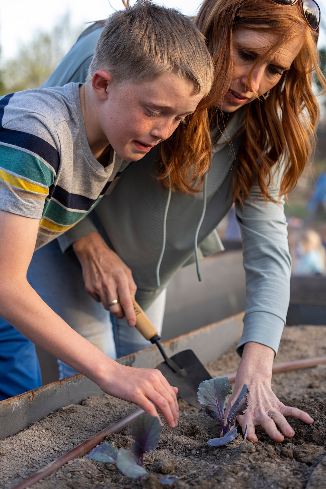 (Rick Egan | The Salt Lake Tribune)  Jacob watches as his mom, Jennie Taylor helps her son Jacob plant a cabbage, during the Earth Day Party at the Mini Taylor farm at at the Jennie Taylor's residence, in North Ogden. Taylor is the widow to the late Major. Brent Taylor, killed in 2018 while on Army National Guard duty in Afghanistan, donations have helped restore the small family farm, with planter boxes, a chicken coop, and a sandbox for the kids, on Thursday, April 22, 2021.