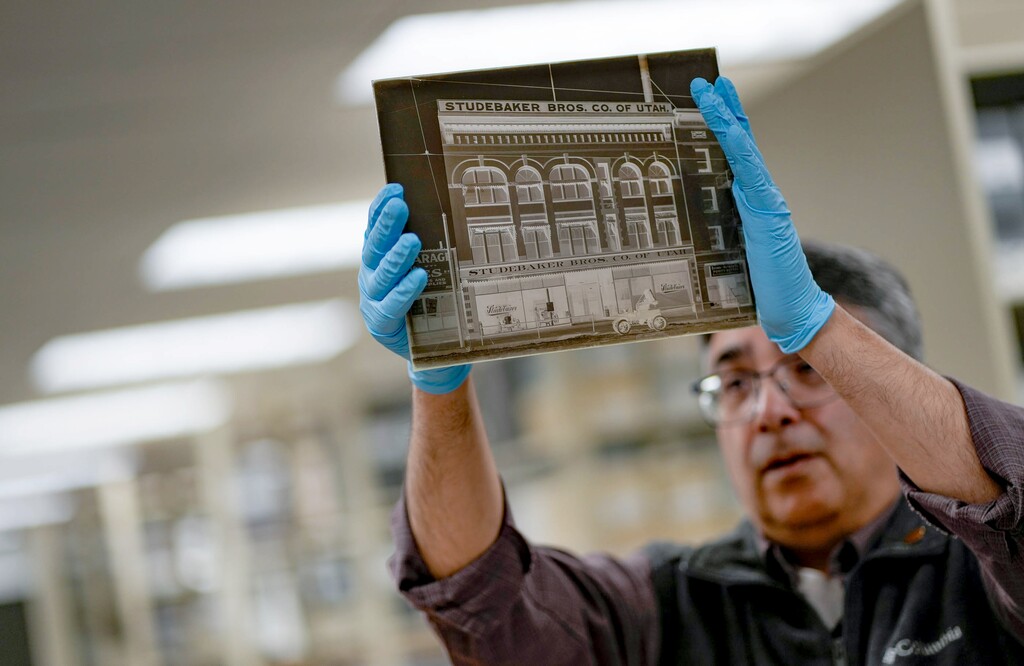 (Francisco Kjolseth | The Salt Lake Tribune) Doug Misner, research and collections manager with Utah State History holds up an 8x10 glass negative featuring a Studebaker Bros. storefront dating back to 1911 on Friday, Jan. 13, 2023. The format popular in the 1850s is one of 10,000 glass plate images from the Shipler family commercial photographers collection housed at the Midvale Collections center.