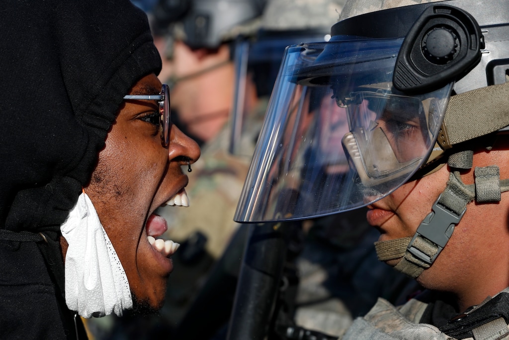 Protesters and National Guardsmen face off on East Lake Street, Friday, May 29, 2020, in St. Paul, Minn.  The massive protests sweeping across U.S. cities following the police killing of a black man in Minnesota have elevated fears of a new surge in cases of the coronavirus. Images showing thousands of screaming, unmasked protesters have sent shudders through the health community, who worry their calls for social distancing during the demonstrations are unlikely to be heard.   (AP Photo/John Minchillo)