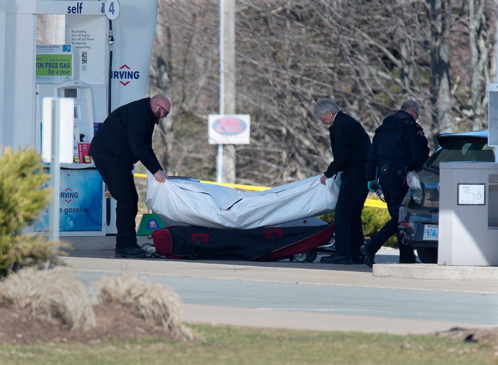 (Andrew Vaughan | The Canadian Press via AP) Workers with the medical examiner's office remove a body from a gas station in Enfield, Nova Scotia, on Sunday, April 19, 2020. A suspect in an active shooter investigation was placed in custody Sunday at an Irving service station in Nova Scotia, after police said there were multiple victims' in a shooting that began in a small coastal village where frightened local residents took cover in their basements overnight.