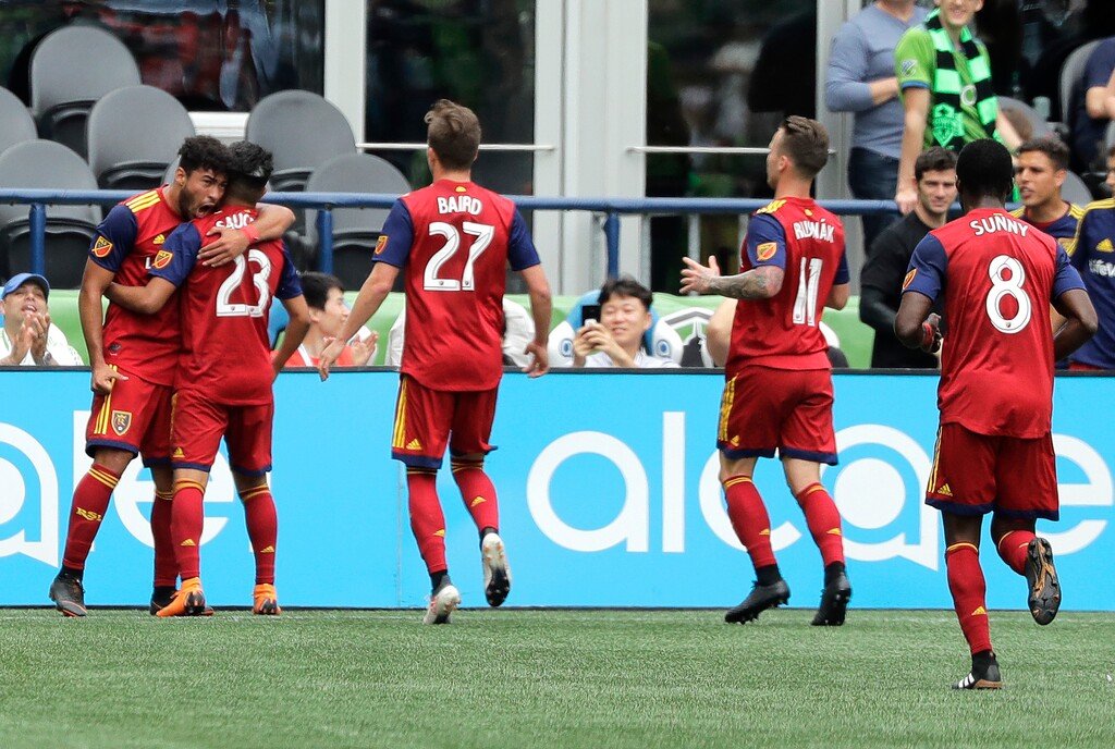Real Salt Lake's Sebastian Saucedo, second from left, is greeted by Danilo Acosta, left, after Saucedo scored a goal against the Seattle Sounders during the second half of an MLS soccer match Saturday, May 26, 2018, in Seattle. Real Salt Lake won 1-0. (AP Photo/Ted S. Warren)