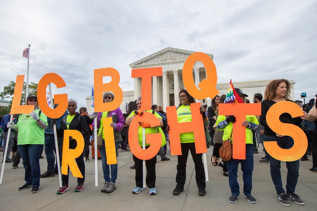 FILE - In this Oct. 8, 2019, file photo, supporters of LGBTQ rights hold placards in front of the U.S. Supreme Court in Washington.
