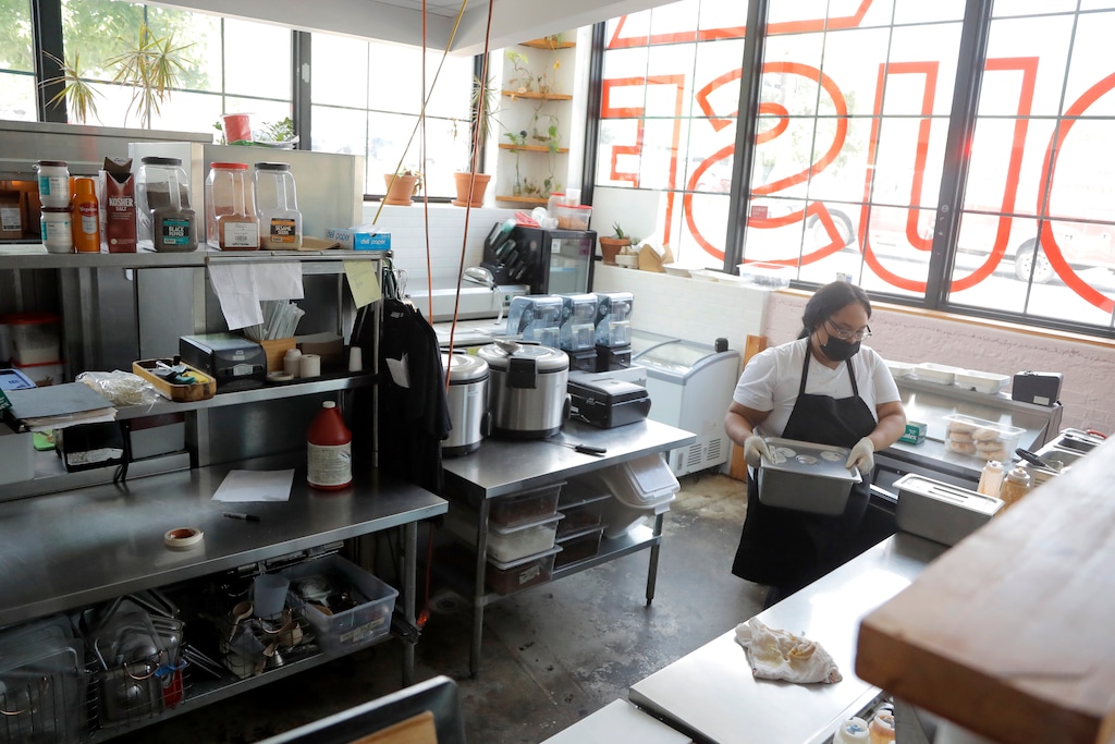 (Julio Cortez | AP) An employee of a food establishment works behind the counter at the R. House food hall, Wednesday, July 15, 2020, in Baltimore. The hall, which houses a variety of restaurants, has modified its seating areas as well as implementing an order and pay by phone system to ensure contactless transactions between restaurant operators and customers.