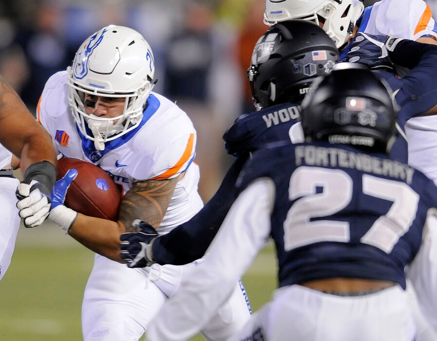 Boise State running back Ryan Wolpin (21) carries the ball as Utah State linebacker David Woodward (9) and cornerback Deante Fortenberry (27) defend during an NCAA college football game, Saturday, Oct. 28, 2017, in Logan, Utah. (Eli Lucero/Herald Journal via AP)/The Herald Journal via AP)