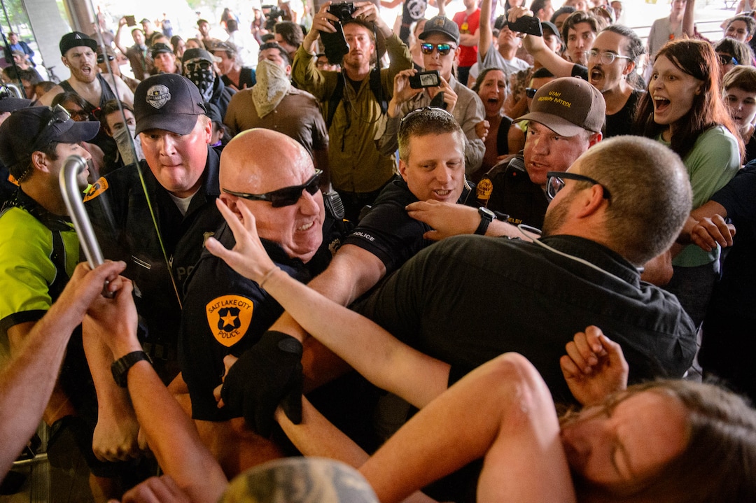 (Trent Nelson  |  The Salt Lake Tribune)  Police struggle with protesters for control of a door at the Chamber of Commerce Building Salt Lake City on Tuesday, July 9, 2019. Dozens of people showed up to protest the proposed Inland Port and ended up clashing with police, resulting in temporary street closures and arrests.