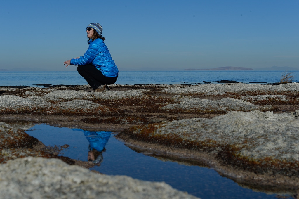 (Francisco Kjolseth | The Salt Lake Tribune) Bonnie Baxter, a biologist with Utah's Westminster College, is reflected amongst the small pools of salt water that surround the dome like structures she is studying known as microbialites.