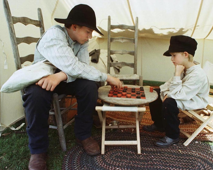 Rick Egan  | Tribune File Photo 

Jason Stout, 14 Orem, passes the time by playing a game of  checkers on a painted wooden table with Robert Lowe, 7, Orem, along the trail in Wyoming. 
