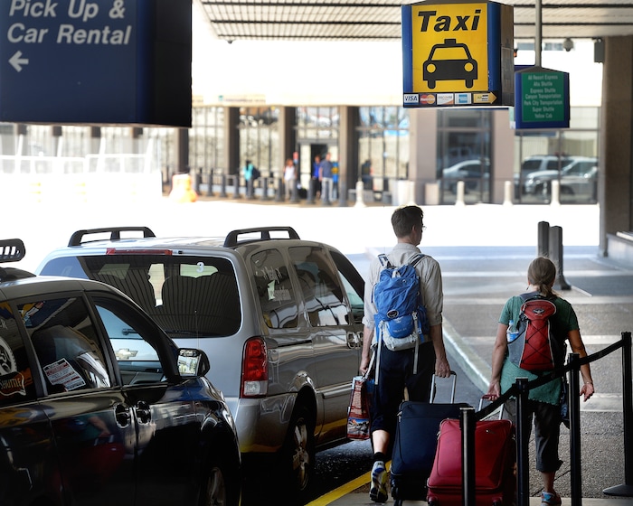 Scott Sommerdorf   |  The Salt Lake Tribune  Travelers walk past the taxi stand at the Salt Lake International Airport, Wednesday, July 20, 2016.  There have been some complaints from airport visitors about largely unregulated taxi fares. Cabs no longer need to have meters, can largely charge any fare they want (with some exceptions in SLC itself), and need not tell passengers in advance how much they will charge.