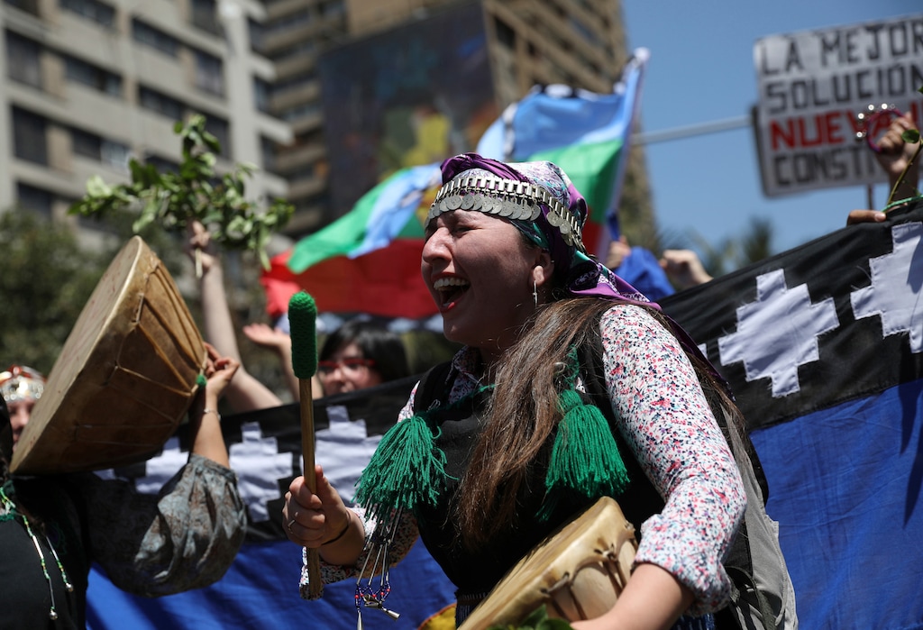 (Rodrigo Abd | AP file photo)  A Mapuche indigenous woman beats on a drum during an anti-government protest in Santiago, Chile, Thursday, Oct. 24, 2019. Chile has been facing days of unrest, triggered by a relatively minor increase in subway fares. The protests have shaken a nation noted for economic stability over the past decades, which has seen steadily declining poverty despite persistent high rates of inequality.