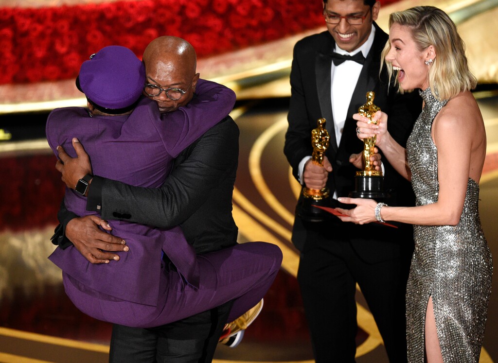 Samuel L. Jackson, center left, embraces Spike Lee, winner of the award for best adapted screenplay for "BlacKkKlansman" as Brie Larson, right, looks on, at the Oscars on Sunday, Feb. 24, 2019, at the Dolby Theatre in Los Angeles. (Photo by Chris Pizzello/Invision/AP)
