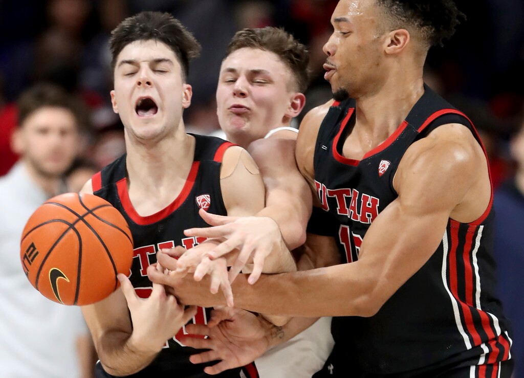 Arizona guard Pelle Larsson, center, is squeezed between Utah guards Lazar Stefanovic, left, and Marco Anthony, right, while fighting through a pick in the first half of an NCAA college basketball game in Tucson, Ariz., Saturday, Jan. 15, 2022. (Kelly Presnell/Arizona Daily Star via AP)