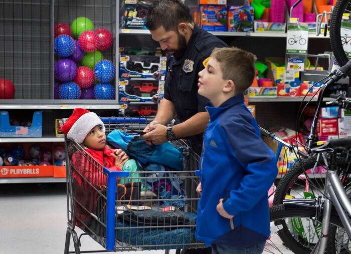 (Scott Sommerdorf   |  The Salt Lake Tribune)   Talon Havens, right, shops with Officer George Uyema and his daughter Isabelle at the first ever Police Pay It Forward event, Saturday, December 16, 2017.  