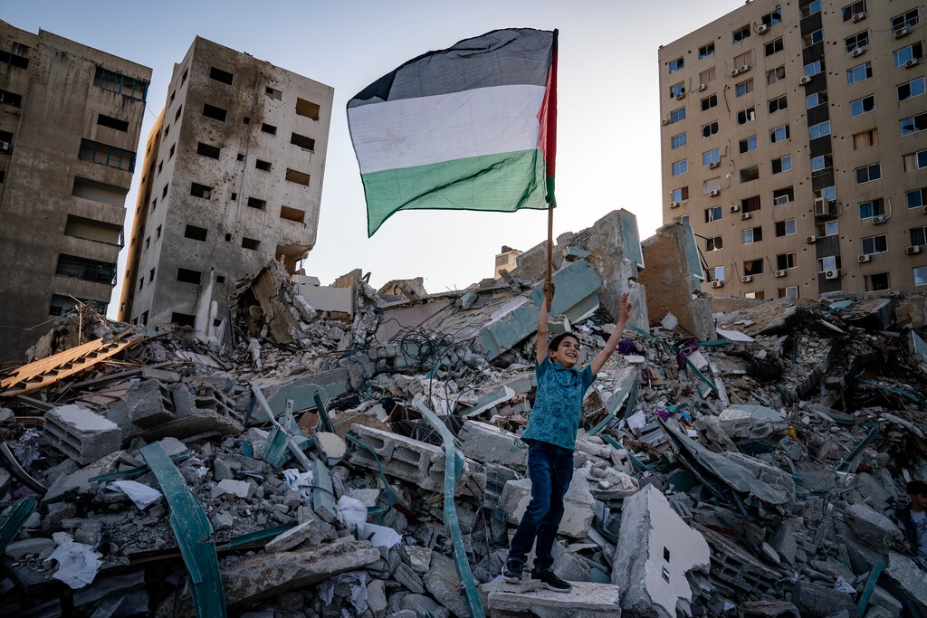 A child raises a Palestinian flag and cheers as spectators gather beside the rubble of the al-Jalaa building following a cease-fire in Gaza City, Friday, May 21, 2021. The building was the home of the Associated Press bureau in Gaza City for 15 years. (AP Photo/John Minchillo)