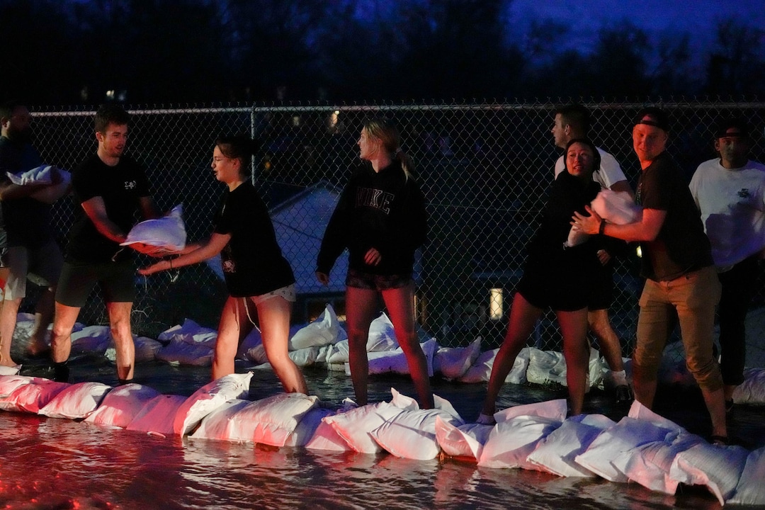 (Francisco Kjolseth | The Salt Lake Tribune) People work to protect homes into the night along 1700 South in Salt Lake City from the rising flow of Emigration Creek through Wasatch Hollow Park on Wednesday, April 12, 2023. 