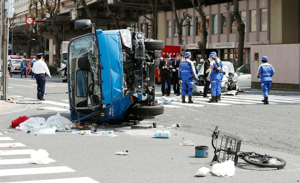 Police officers inspect the scene of a car accident in Tokyo Friday, April 19, 2019. A car, right rear, driven by an 87-year-old man crashed into a garbage truck, foreground, on a Tokyo street Friday, killing a woman and a girl who were on a bicycle, according to police. (Shinji Kita/Kyodo News via AP)