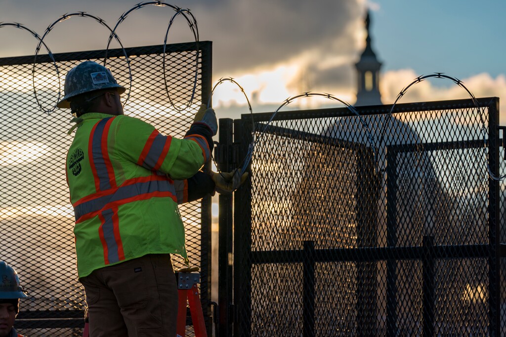 FILE - In this Jan. 18, 2021, file photo, workers install razor wire atop fencing around the U.S. Capitol perimeter at sunset, in Washington. (AP Photo/J. Scott Applewhite, File)