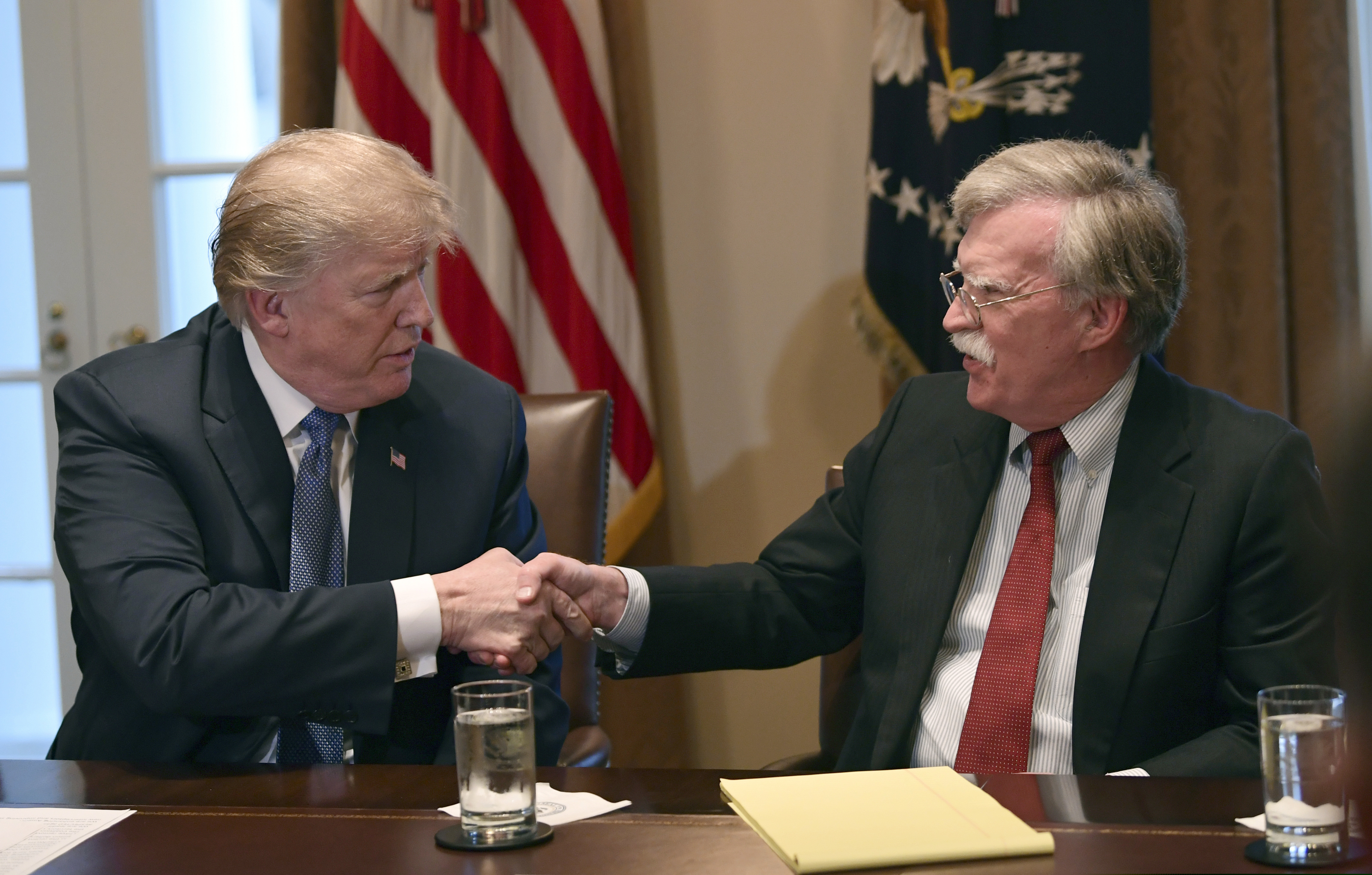 FILE - In this April 9, 2018 file photo, President Donald Trump, left, shakes hands with national security adviser John Bolton in the Cabinet Room of the White House in Washington at the start of a meeting with military leaders. (AP Photo/Susan Walsh)