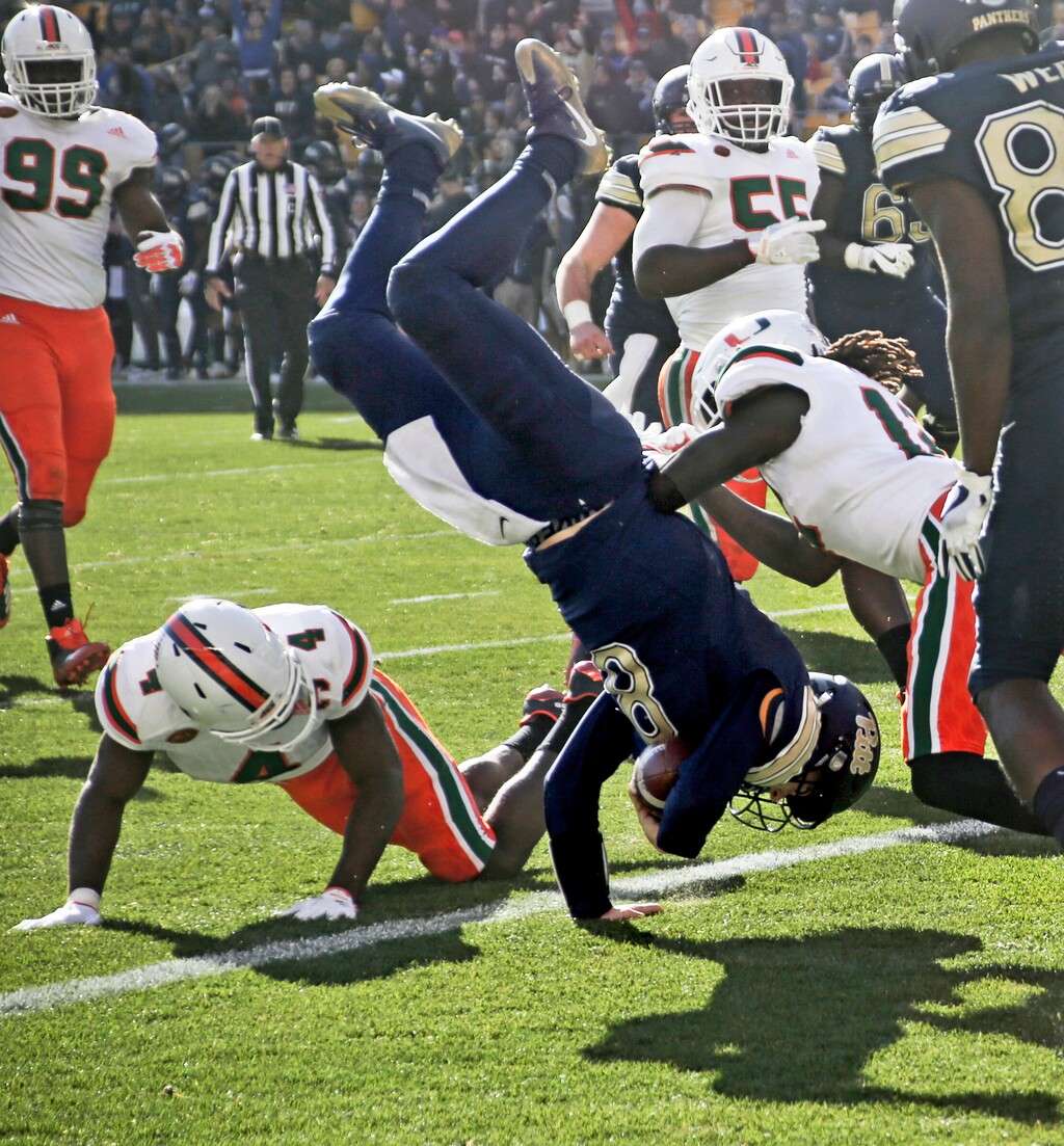 Pittsburgh quarterback Kenny Pickett (8) flips over Miami defensive back Jaquan Johnson (4) as he goes in for a touchdown in the first half of an NCAA college football game, Friday, Nov. 24, 2017, in Pittsburgh. (AP Photo/Keith Srakocic)