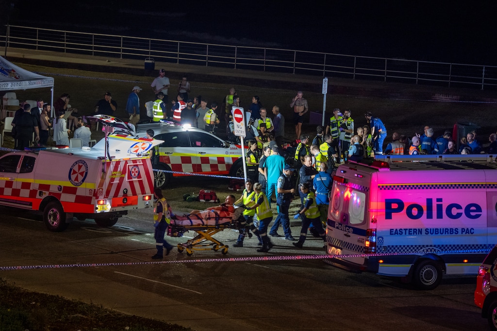 (Matthew Abbott | The New York Times) Emergency workers transport a person by stretcher from the scene of a mass shooting at Bondi Beach, in Sydney, on Sunday, Dec. 14, 2025.
