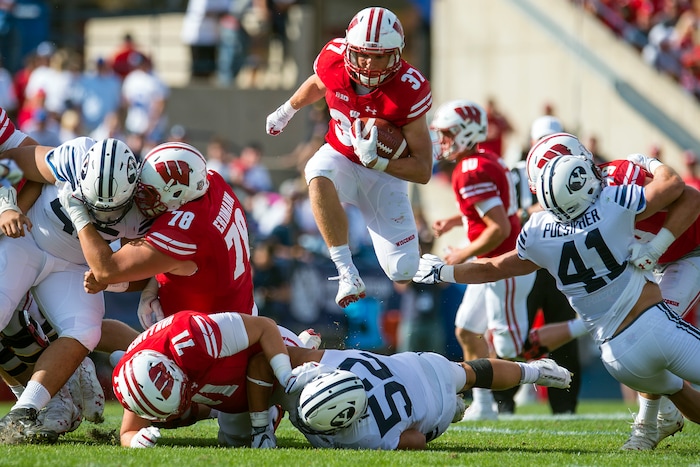 (Chris Detrick  |  The Salt Lake Tribune)   Wisconsin Badgers running back Garrett Groshek (37) leaps over Brigham Young Cougars defensive lineman Trajan Pili (52) during the game at LaVell Edwards Stadium Saturday Saturday, September 16, 2017. Wisconsin Badgers defeated Brigham Young Cougars 40-6.