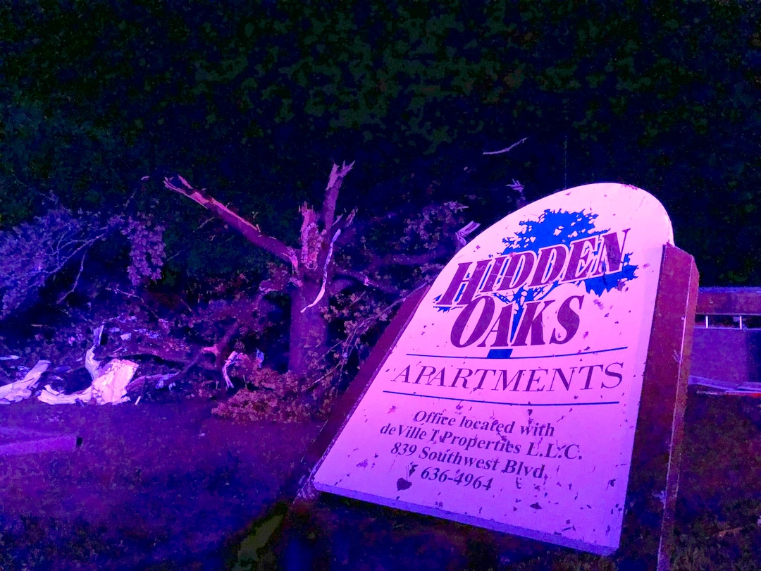 (David A. Lieb | AP) The sign for the Hidden Oaks apartment complex in Jefferson City Missouri stands bent on May 23, 2019, from an apparent tornado in front of a tree that was ripped apart. A "violent tornado" touched down in Jefferson City, Missouri, causing possible fatalities, according to the National Weather Service.