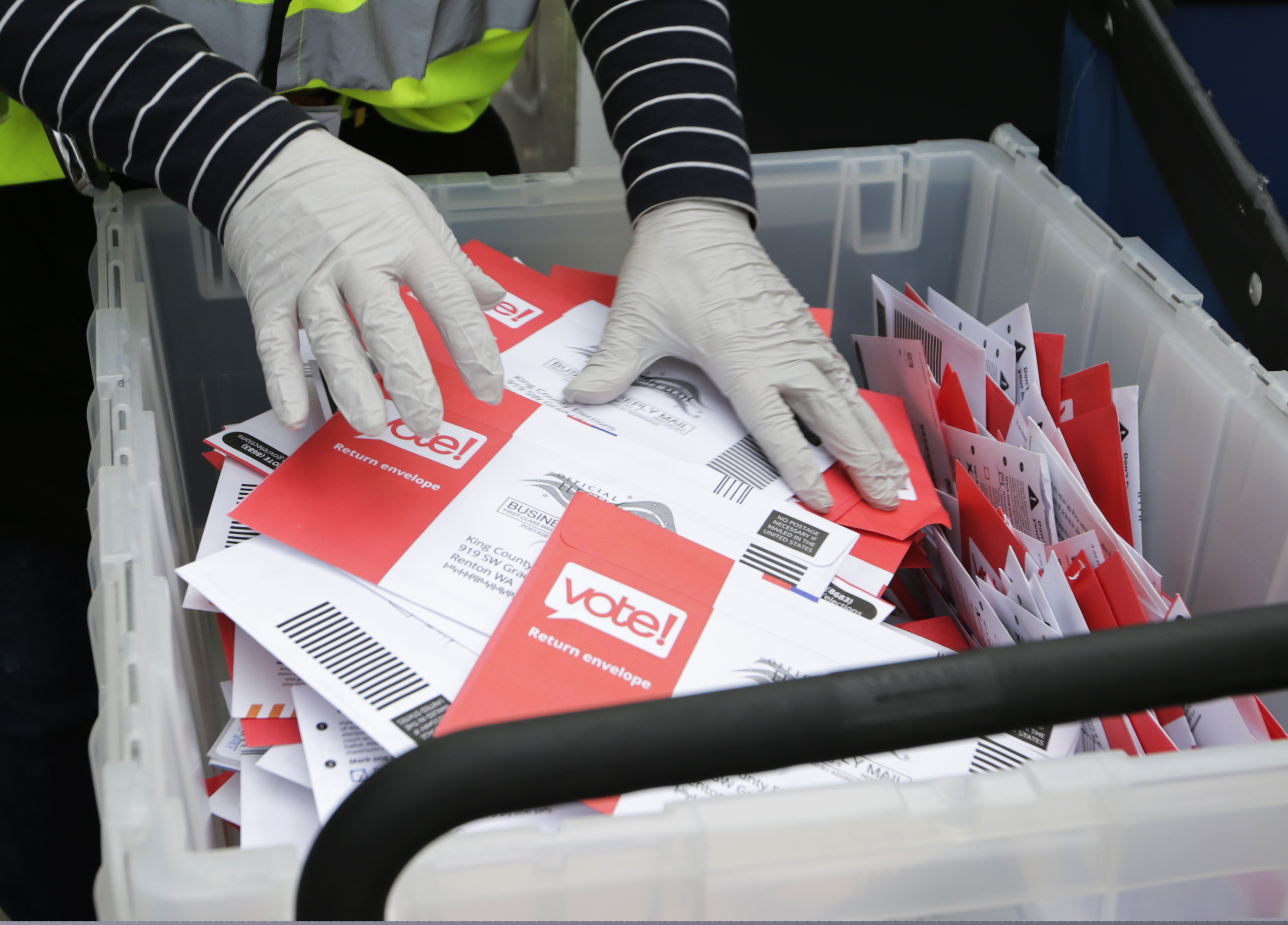 (John Froschauer | AP file photo) A King County Election worker collect ballots from a drop box in the Washington State primary, in Seattle on March 10, 2020. The 2020 presidential election is creeping ever closer, and there are no signs yet of pandemic abating, nor any word on when Americans on orders to stay home can resume normal life, and so lawmakers are trying to figure how to allow for voting in a world where face-to-face contact causes anxiety at the least, and sickness and death at the most.