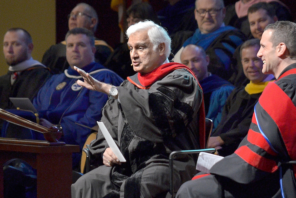 (Jeff Morehead/The Chronicle-Tribune via AP) In this March 30, 2016, file photo, Ravi Zacharias, center, speaks during the Society of World Changers induction ceremony at Indiana Wesleyan University in Marion, Ind. A law firm's investigators have released a scathing report on their four-month investigation of alleged sexual misconduct by Zacharias, who founded a global Christian ministry that bears his name.