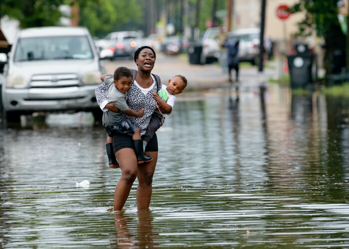 (Matthew Hinton | AP Photo) Terrian Jones reacts as she feels something moving in the water at her feet as she carries Drew and Chance Furlough to their mother on Belfast Street in New Orleans during flooding from a storm in the Gulf Mexico that dumped lots of rain Wednesday, July 10, 2019.