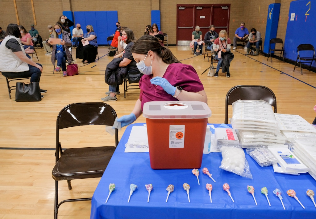 (Leah Hogsten | The Salt Lake Tribune) Nurse Jana Arnold, disinfecting her covid-19 vaccination work space on Friday, didn't have many adults taking the dumdum suckers she placed on her table. Employees of the Jordan School District were invited to West Hills Middle School to receive their coronavirus vaccination, Feb. 12, 2021. 