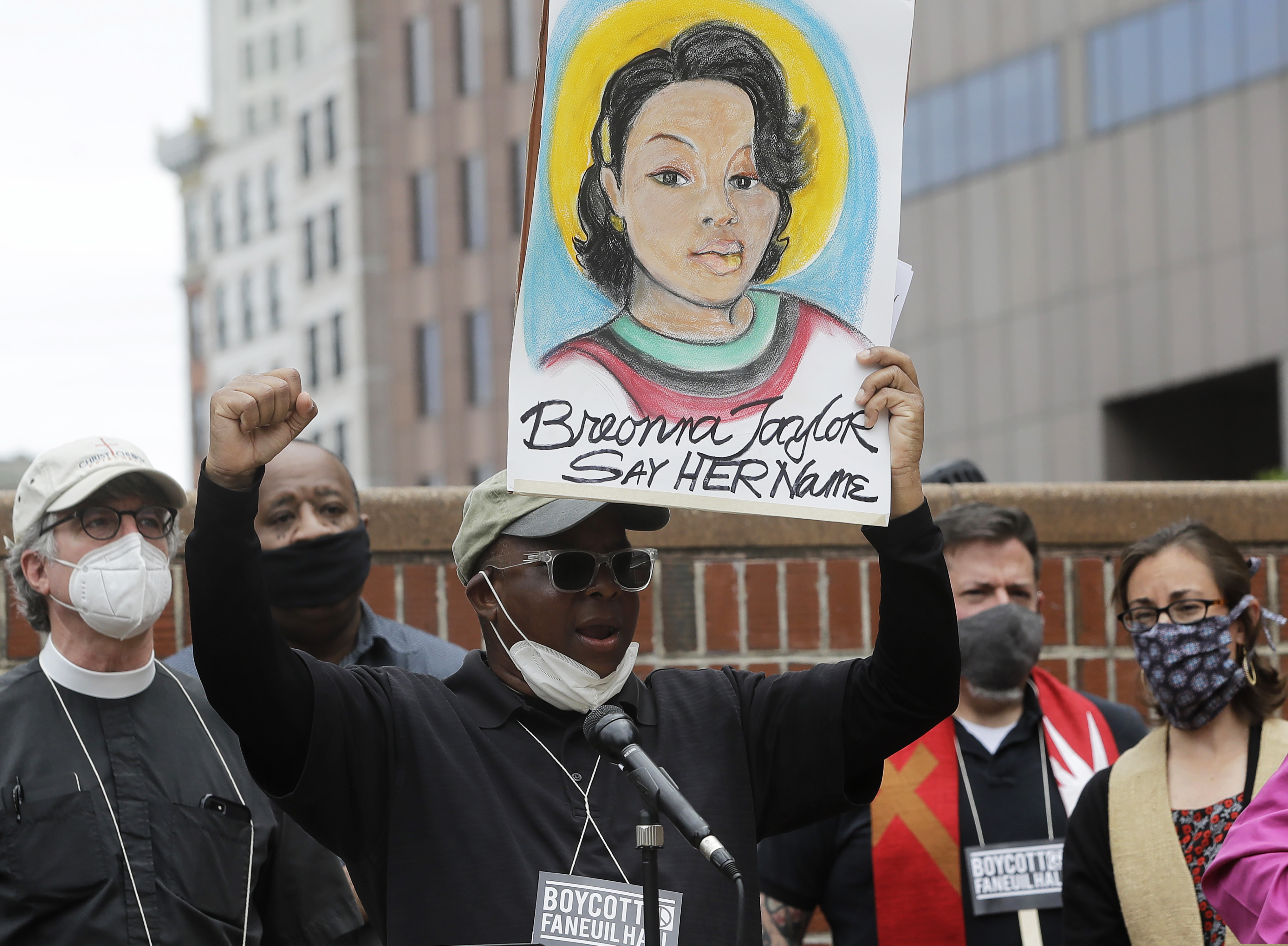 (Steven Senne | AP file photo) Kevin Peterson, center, founder and executive director of the New Democracy Coalition, displays a placard showing fallen Breonna Taylor as he addresses a rally in Boston on June 9, 2010. Louisville’s mayor said Friday, June 19, 2020, that one of three police officers involved in the fatal shooting of Breonna Taylor will be fired.