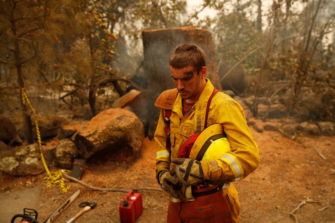 Shawn Slack rests after felling trees burned in the Camp Fire, Monday, Nov. 12, 2018, in Paradise, Calif. (AP Photo/John Locher)