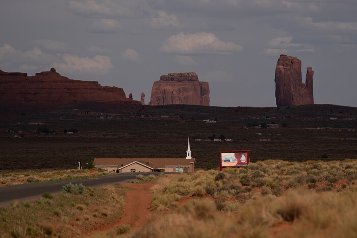 The mesas of Monument Valley are seen beyond the Church of Jesus Christ of Latter-day Saints in Oljato-Monument Valley, Utah on the Navajo Reservation April 30, 2020. The reservation has some of the highest rates of coronavirus in the country. If Navajos are susceptible to the virus' spread in part because they are so closely knit, that's also how many believe they will beat it. (AP Photo/Carolyn Kaster)