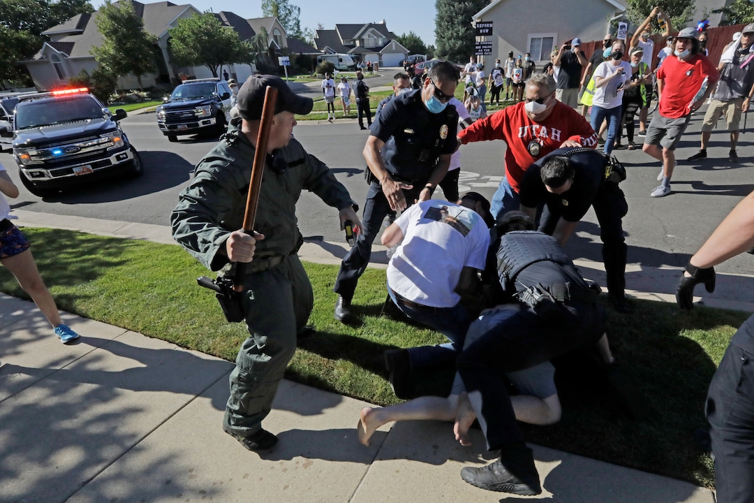 Protesters are tackled by Cottonwood Heights police officers during a march Sunday, Aug. 2, 2020, in Cottonwood Heights, Utah. The protest was a "March for Justice" focused largely around Zane James, who was fatally shot by police in Cottonwood Heights in 2018. (AP Photo/Rick Bowmer)