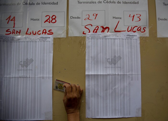People look for their names on voter registration lists outside a polling station during regional elections in Caracas, Venezuela, Sunday, Oct. 15, 2017. Elections could tilt a majority of the states' 23 governorships back into opposition control for the first time in nearly two decades of socialist party rule, though the government says the newly elected governors will be subordinate to a pro-government assembly. (AP Photo/Fernando Llano)