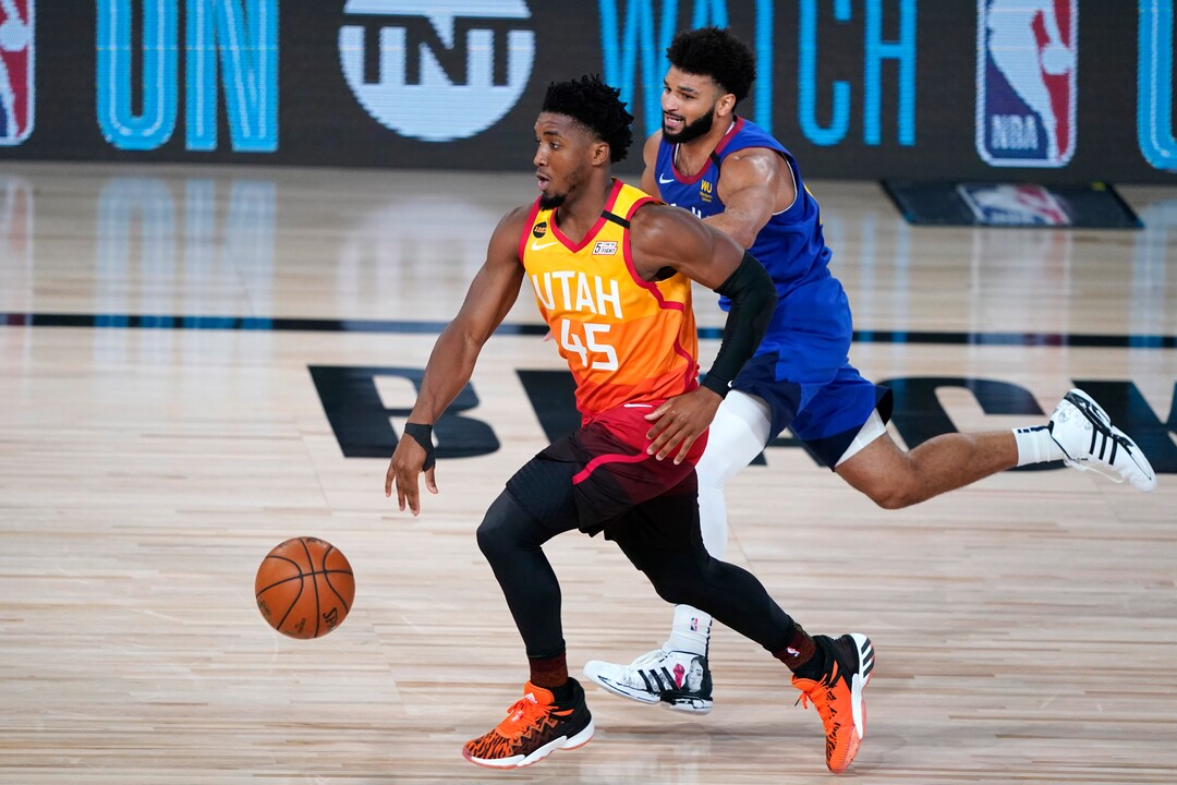 Utah Jazz's Donovan Mitchell (45) brings the ball up the court as Denver Nuggets' Jamal Murray defends during the first half of an NBA basketball first round playoff game Sunday, Aug. 30, 2020, in Lake Buena Vista, Fla. (AP Photo/Ashley Landis)