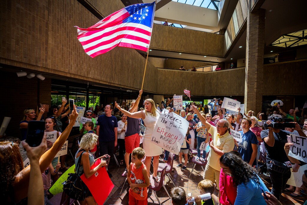 (Trent Nelson  |  The Salt Lake Tribune) People sing the National Anthem under a Three Percenter flag after the Salt Lake County Council voted down Dr. Angela Dunn's mask ordinance for K-6 students, on Thursday, Aug. 12, 2021.