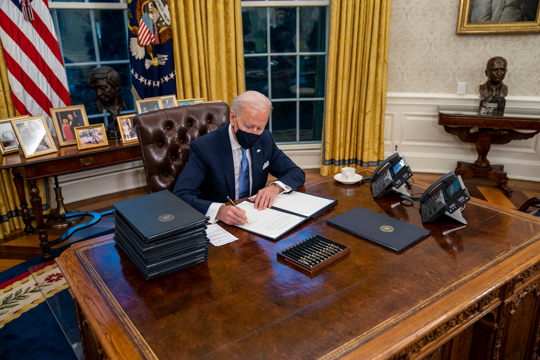 President Joe Biden signs executive orders during his first minutes in the Oval Office of the White House in Washington, on Inauguration Day, Wednesday, Jan. 20, 2021. (Doug Mills/The New York Times)