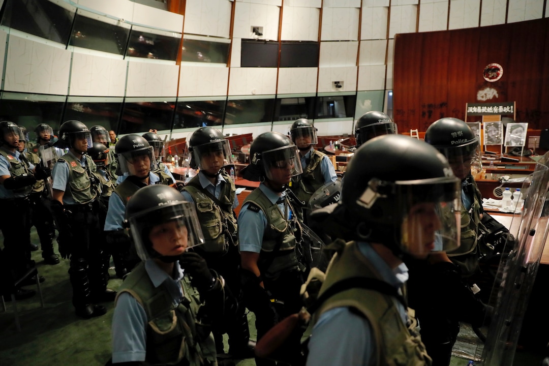 (Kin Cheung | AP Photo) Police officers with protective gear retake the meeting hall of the Legislative Council in Hong Kong, during the early hours of Tuesday, July 2, 2019. Hundreds of protesters in Hong Kong swarmed into the legislature's main building Monday night, tearing down portraits of legislative leaders and spray-painting pro-democracy slogans on the walls of the main chamber as frustration over a lack of response from the administration to opposition demands boiled over.