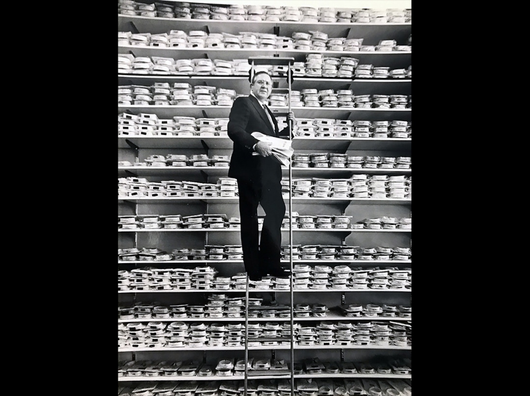 (Tom Kelly | Tribune file photo) Mac Christensen, the man behind the Mr. Mac clothing stores, poses on a ladder along shelves of dress shirts in the spring of 1990 in what was then his new store at 135 S. Main St. in Salt Lake City.  Christensen died Oct. 11, 2019, at age 85.