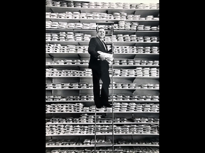 (Tom Kelly | Tribune file photo) Mac Christensen, the man behind the Mr. Mac clothing stores, poses on a ladder along shelves of dress shirts in the spring of 1990 in what was then his new store at 135 S. Main St. in Salt Lake City. Christensen died Oct. 11, 2019, at age 85.