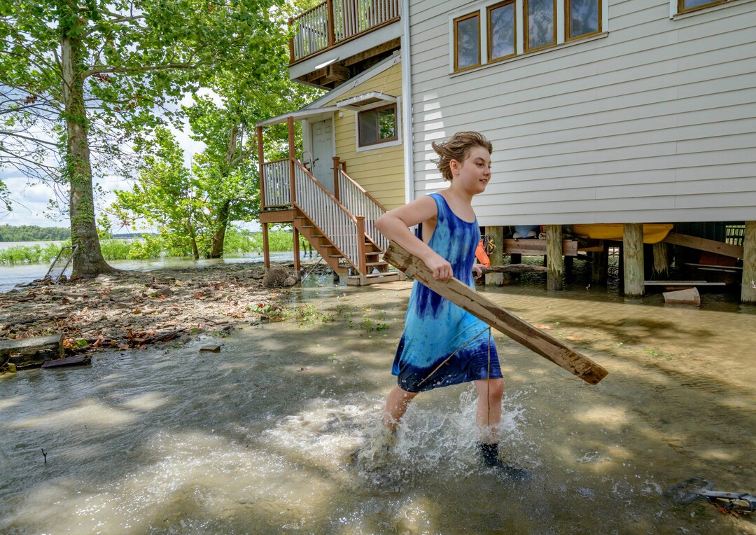 (Matthew Hinton | AP Photo) Tallulah Campbell, 8, clears out driftwood and other debris in preparation of Tropical Storm Barry near New Orleans, La., Thursday, July 11, 2019. The area is normally a driveway at her family's home that is one of the few on land called batture on the outside of the Mississippi River levee at the border of Orleans and Jefferson Parishes.